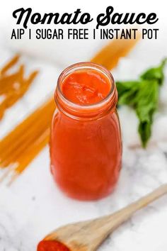 a jar of tomato sauce next to a wooden spoon