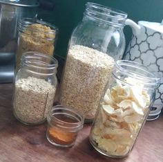 several jars filled with food sitting on top of a wooden table next to a blender