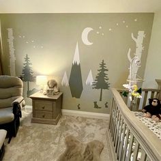 a baby's room decorated in gray and white with trees on the wall, teddy bear crib