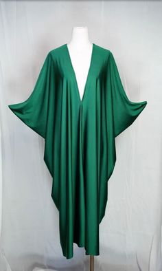 Introducing the Huntress Caftan, a must-have for any fashion-forward individual. This exquisite garment is more than just a piece of clothing; it's a celebration of fabric in all its glory. Crafted with high-quality emerald green jersey and lots of love, this piece offers an airy fit designed to drape beautifully on all body types. Whether worn poolside for a day at the cabana or layered and adorned with your favorite accessories for a glamorous evening affair, it's a versatile wardrobe staple that effortlessly adapts to your every mood and occasion. Bohemian splendor, handmade in California. Our caftans are a voluminous one-size fits all garment, approximately 50" in length. The intention of this shape is to celebrate the magic of fabric and its captivating dance with form. JG one-size ca Elegant Green Maxi Dress For Festival, Long Kaftan For Spring Evening, Long Evening Kaftan For Spring, Long Kaftan For Evening In Spring, Long Kaftan For Evening And Spring, Long Summer Evening Kaftan, Spring Party Tunic Kaftan, Elegant Maxi Dress With Kimono Sleeves For Festival, Fitted Kaftan For Summer Evening