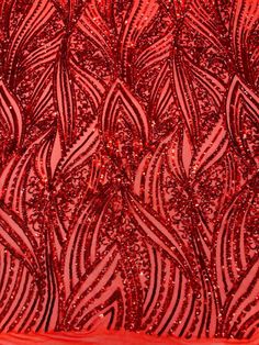 red sequins on fabric with wavy lines and curves in the center, closeup