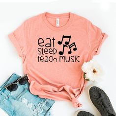 "Eat Sleep Teach Music T-shirt, Teaching Shirt, Musician Tee, School Gift, Music Lover Shirt, Teacher Tee, School Tops, Teacher Gift, Teacher Shirts, Teacher T-shirts, Teacher Tees, Teacher Appreciation, Gift For Teacher, Funny Teacher Shirt, Cute Teacher Tee, Teacher Love Shirt, Best Teacher Shirt, Love Teachers, Caring Teacher, New Teacher Gift This updated unisex essential fits like a well-loved favorite. Super soft cotton and excellent quality print makes one to fall in love with it over and over again. ------------- Fabrication ------------- 100% Combed ring spun cotton Made by specially treating the cotton fibers before spinning them into yarn. The result is stronger and smoother fabric. ------------- Unisex T-shirt Size Chart ------------- XS - - 27\" Length and 18\" Width S - 28\" Music-themed Slogan Crew Neck Top, Music-themed Slogan Tops With Crew Neck, Music-themed Slogan Top With Crew Neck, Music Festival Cotton T-shirt With Letter Print, Cotton T-shirt With Letter Print For Music Festival, Letter Print Cotton T-shirt For Music Festival, Music-themed Cotton Tops With Slogan, Music-themed Cotton Slogan Tops, Cotton Music-themed T-shirt With Text Print