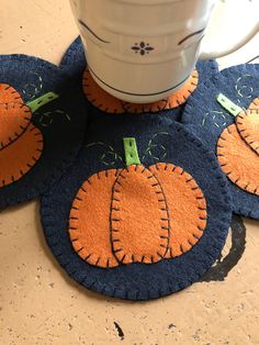 three pumpkin shaped rugs on the floor next to a coffee cup