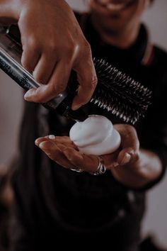 a person holding a hair dryer in their hand and using it to brush the hair