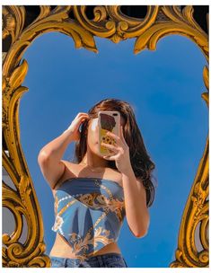 a woman taking a selfie in front of a golden mirror with her cell phone