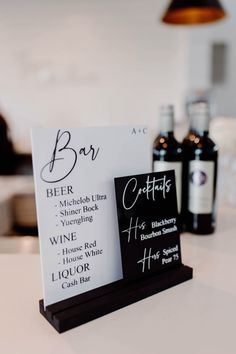 a sign that is on top of a table with wine bottles in the back ground