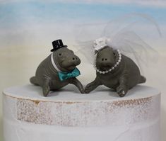 two small figurines are sitting on top of a cake