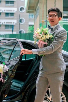 a man in a suit getting out of a car with flowers on his lapel