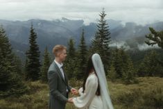 a bride and groom walking in the mountains