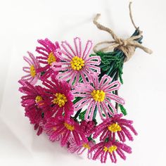 a bunch of pink and yellow flowers on a white surface with a string tied to it