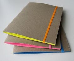 three notebooks stacked on top of each other with different colored papers in front of them