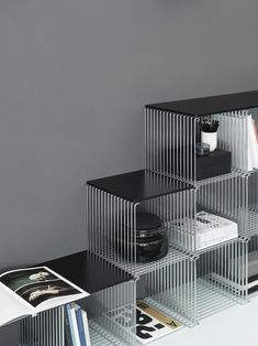 three metal shelvings stacked on top of each other in front of a gray wall