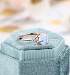 an engagement ring sitting on top of a blue velvet box with a white diamond in the center