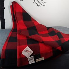 a red and black plaid blanket sitting on top of a couch next to a wall