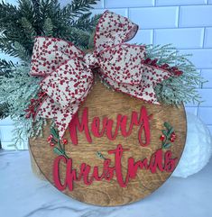 a wooden sign that says merry christmas with red and white bows on it's head