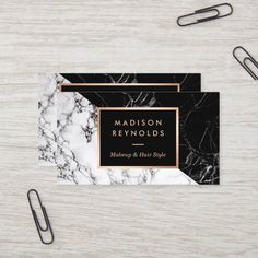 black and white marble business card with gold foil on the front, next to a pair of paper clips