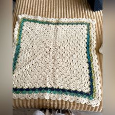 a white crocheted blanket sitting on top of a wooden floor next to a pair of shoes