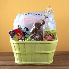 a green basket filled with lots of different types of items on top of a wooden table