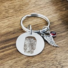 a metal keychain with a fingerprint on it and a red bead