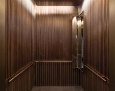 an empty room with wooden walls and metal handrails on the wall, in front of a mirror