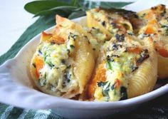 a white bowl filled with pasta and spinach on top of a green table cloth