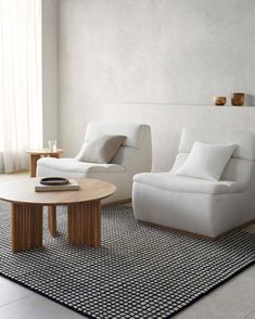 a living room with two white couches and a coffee table in front of a window