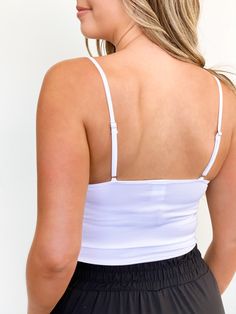 a woman wearing a white tank top and black shorts with her back to the camera