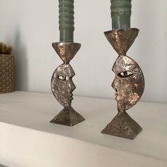 two metal candlesticks with faces on them