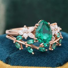 a ring with green and white stones on it sitting on a blue velvet cushioned surface