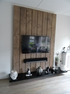 a flat screen tv mounted to the side of a wooden wall next to a shelf