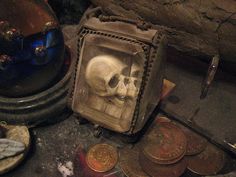 a skull in a glass case next to some coins