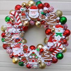 a wreath decorated with christmas ornaments and santa clause on the side of a house door