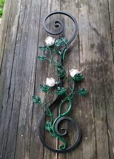 a wrought iron rose and leaf decoration on a wooden deck with grass in the background