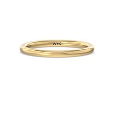 a yellow gold wedding band with the word w c on it's center, in front of a white background