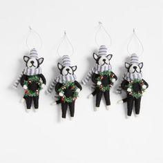 three black and white stuffed animals hanging from strings with christmas wreaths on their backs