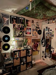 a room filled with lots of records and pictures on the wall next to a bed