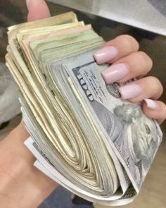 a woman's hand holding stacks of money