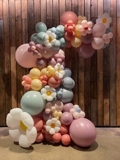 a number made out of balloons and flowers on the floor in front of a wooden wall