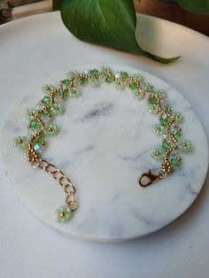 a white marble plate holding a green beaded bracelet