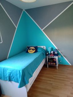 a bed room with a neatly made bed next to a wall painted blue and gray