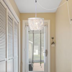 a white chandelier hanging from the ceiling in a room with beige walls and doors