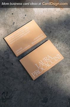 two gold business cards sitting on top of a cement floor with the words, more business card ideas at carddesign com