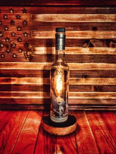 an empty bottle sitting on top of a wooden table next to a wood paneled wall