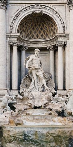 a fountain with statues in front of it and an arch above the water way behind it