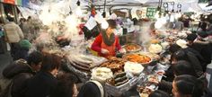 a woman is cooking food at an outdoor market