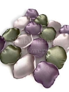 purple and green petals are arranged on a white surface