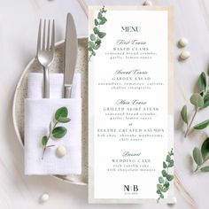 a table setting with silverware, napkins and green leaves on top of it