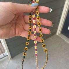 a hand holding a string with flowers and beads on it in front of a door