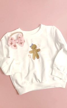 Gingerbread Embroidered Sweater  Toddlers & Girls  TAT: 7-10 days approx. DETAILS:  * Front Design: Embroidered Gingerbread Girl (with bow) design  * Sweater available color:  - Pink   - White  * The sizing of the design will be proportional to the size of the sweater * All options of tees unisex are fit - runs true to size. For an oversized look size up one size.  ** Made to order ** Super comfortable, soft and fashionable. Care Instructions: Please follow these instructions to extend the life Gingerbread Baby, Custom Sweaters, Toddler Sweater, Girls T Shirts, Gingerbread Girl, Embroidered Crewneck, Sweatshirt Crewneck, Embroidered Sweater, Bow Design