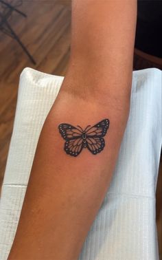 a small butterfly tattoo on the left forearm and arm, with black ink in it